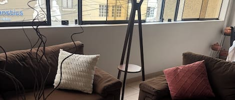 A modern living room with two sofas, a coffee table, a vase with candles, and a view of the outside.