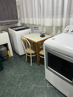 Eine kompakte Küche mit Waschmaschine, Toaster und Tisch mit Stühlen.