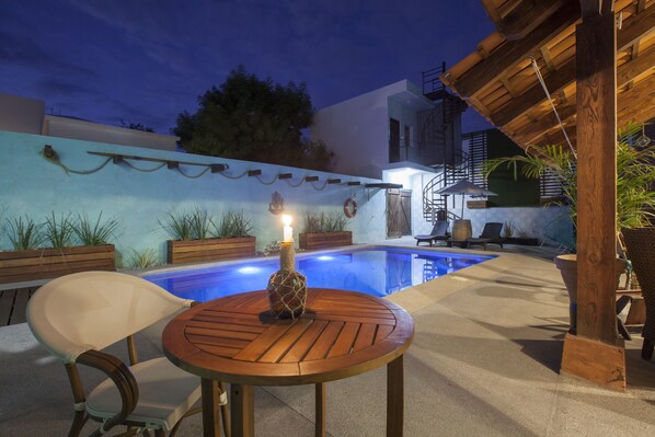 Relax by the pool surrounded by lush greenery and enjoy a meal at the outdoor dining area.