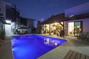Relax by the pool, where a staircase leads to a balcony and lounge chairs invite you to unwind.