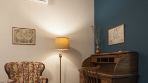 Een kamer met een houten bureau, een stoel, een lamp en een vloerlamp.