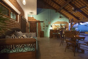 Experience a warm and inviting space with exposed brick walls, wooden beams, and a dining area for communal meals.