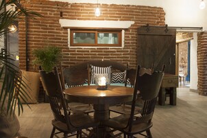 Un comedor rústico con pared de ladrillo, mesa y sillas de madera.