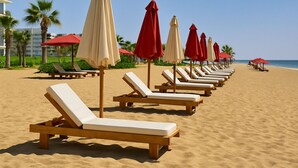 Une plage bordée de rangées de chaises longues et de parasols.