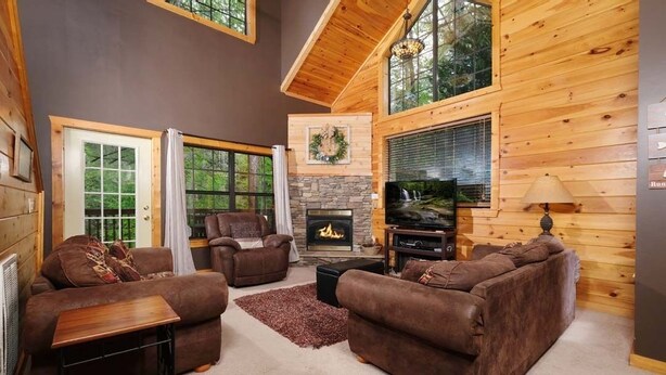 Una sala de estar acogedora con chimenea, sofás de cuero y una base de piedra para la chimenea.