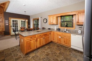 A kitchen with wooden cabinets, a granite countertop, a built-in dishwasher, and a large island with bar stools.