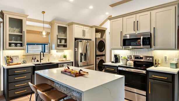 A modern kitchen with a central island, bar stools, stainless steel appliances, and light wood flooring. - Lonetree Ranch an Outdoor Oasis w/ hot tub near Baylor/Magnolia (Waco)