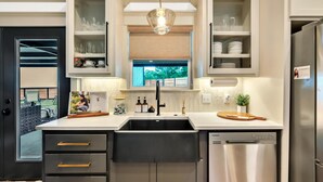 A modern kitchen with a double sink, built-in cabinets, and a stainless steel refrigerator. - Lonetree Ranch an Outdoor Oasis w/ hot tub near Baylor/Magnolia (Waco)