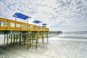 A wooden pier extending into the ocean with blue umbrellas.