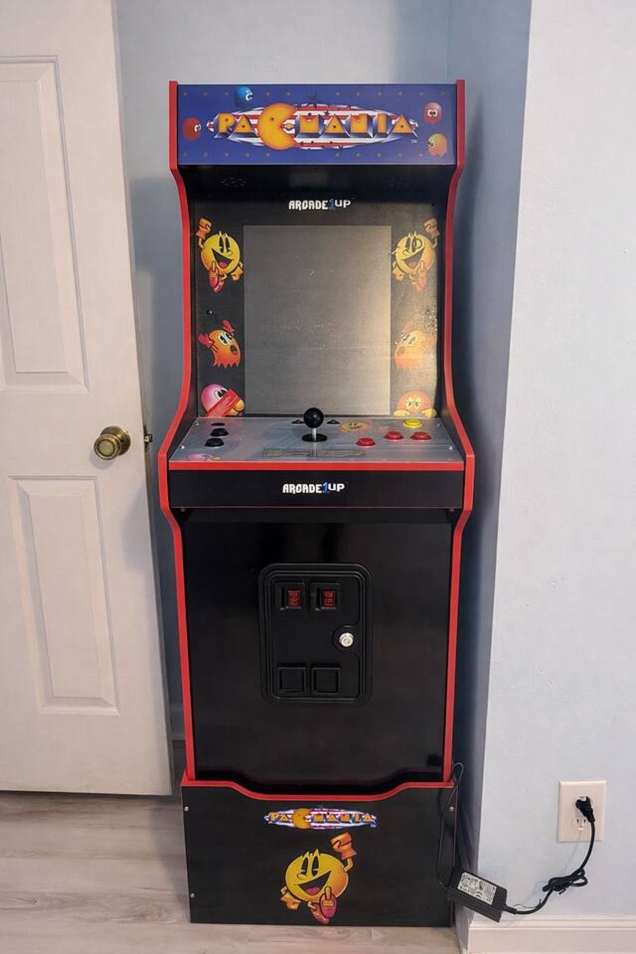 A Pac-Man arcade machine with a red and black color scheme, a coin slot, and a power button.