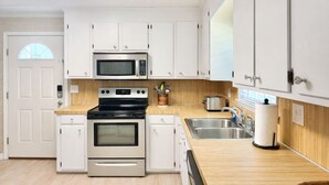 A modern kitchen with white cabinets, a microwave, a stove, and a sink. - Easy Like Sunday ★ Pet-Friendly ★ Walk to Beach ★ Sleeps 10 (Murrells Inlet)