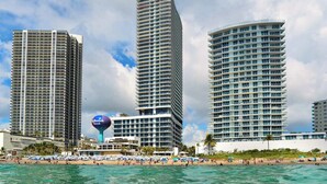 A beachfront hotel with multiple high-rise buildings, a beach with umbrellas, and clear blue water. - Family 2BR | Beach Access | Sleeps 6 (Hollywood)