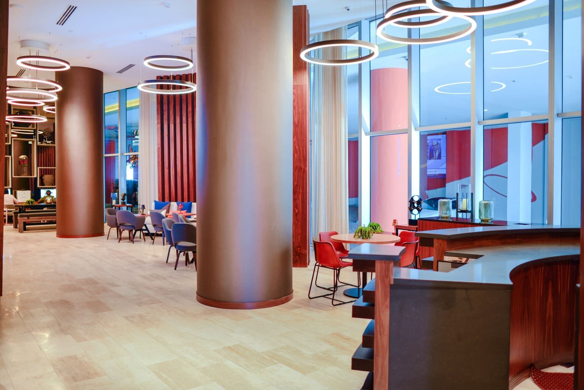 En moderne hotellobby med reception, siddeområde og store vinduer.