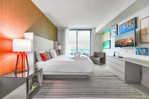 Una habitación de hotel moderna con una cama grande, un escritorio y vistas a la ciudad.