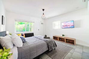 A modern bedroom with a bed, a TV, a window with blinds, and a cityscape view. - Stay Minutes from Miami Hotspots (Miami)