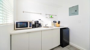 A compact kitchenette with a microwave, coffee maker, sink, and storage cabinets. - Stay Minutes from Miami Hotspots (Miami)