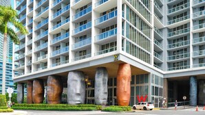 A modern hotel with a distinctive architectural design featuring large, cylindrical columns and a prominent 'W' logo. - 2BR Bay-View Brickell | Steps to City Centre (Miami)
