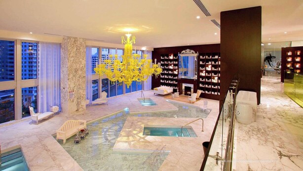 A luxurious hotel lobby with a large indoor pool, a grand chandelier, and a fireplace. - 2BR Bay-View Brickell | Steps to City Centre (Miami)