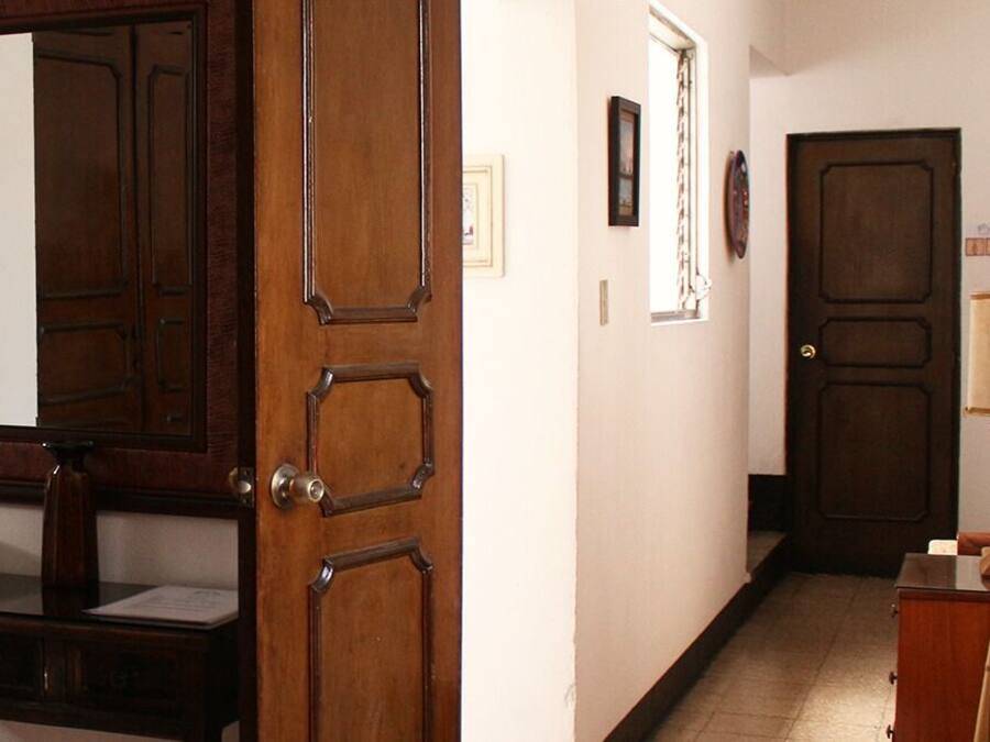 Un pasillo con puerta de madera, un espejo, un cuadro enmarco y una mesita con un cuenco.