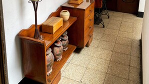 Un pasillo con una consola de madera, un espejo, una lámpara y una puerta.