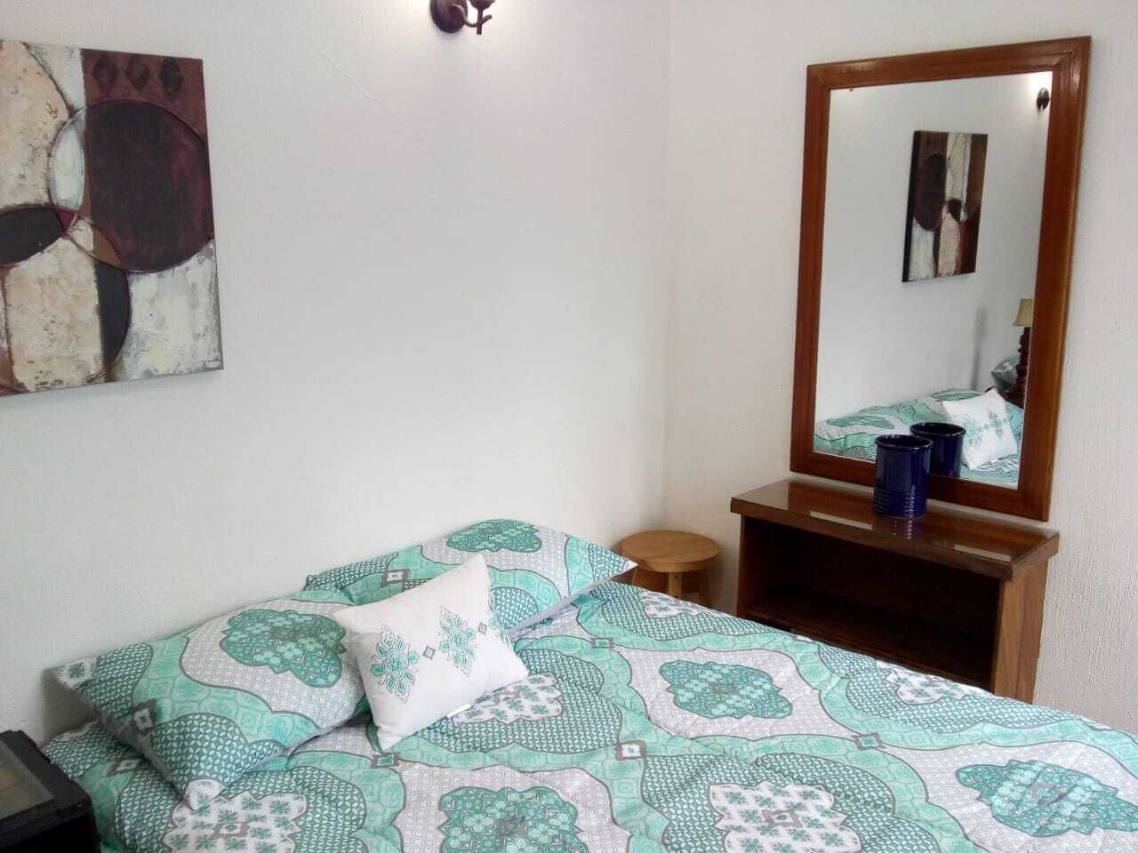 Ein Schlafzimmer mit einem Bett, einem Nachttisch, einem Spiegel und einem Wandbild.