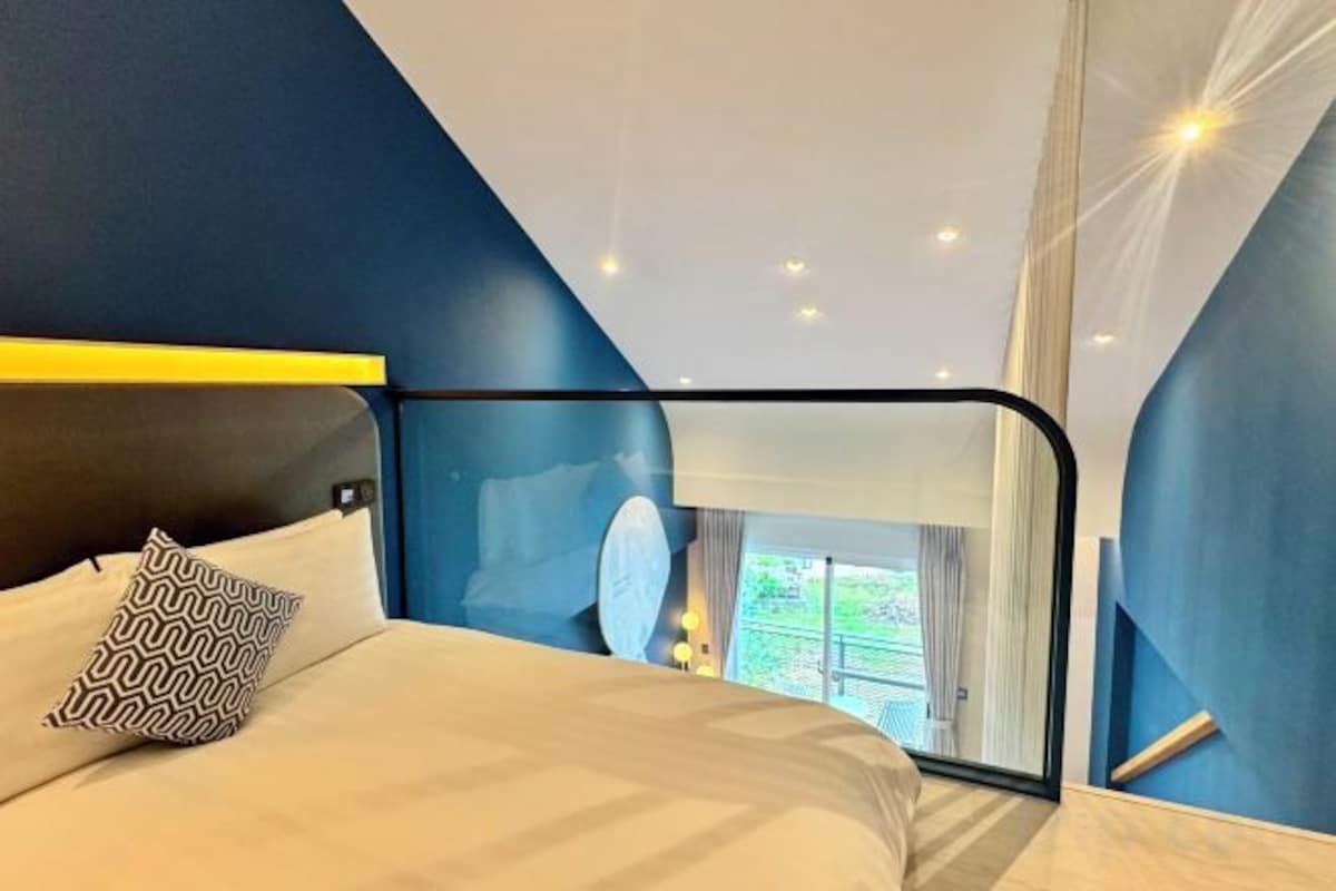 Una habitación de hotel moderna con cama, vistas al exterior y un balcón.