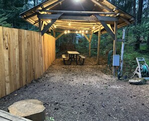 A wooden pergola with string lights, a picnic table, and a gravel ground. - Private RV parking at the base of Mt. Rainier.  Have the forest to yourself! (Packwood)