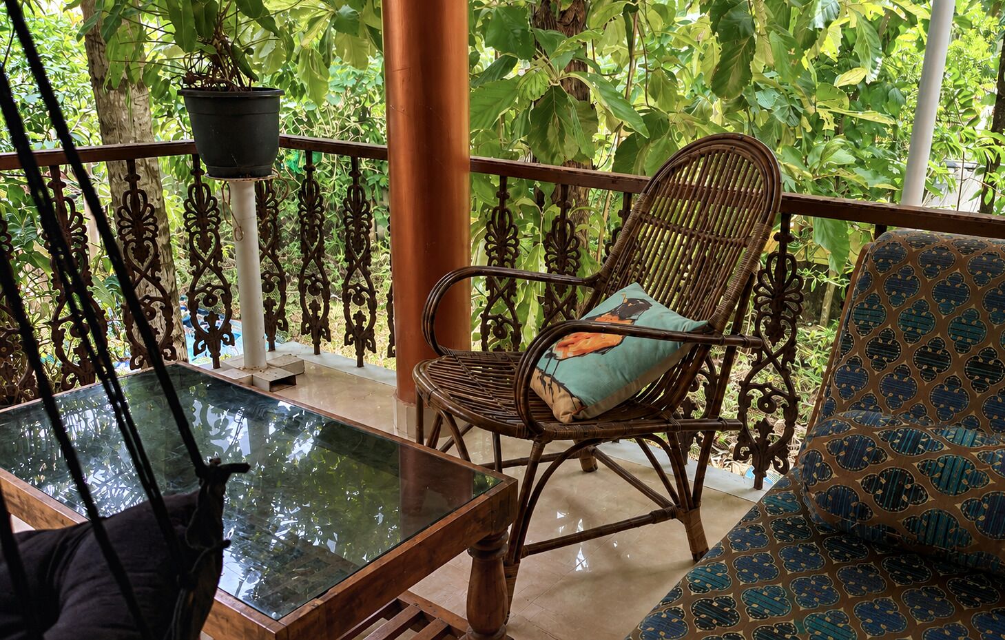 A balcony with a glass table, wicker furniture, and a potted plant.