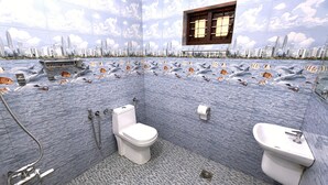 A bathroom with a cityscape mural, a toilet, a bidet, and a sink. - Aryavilla Heritage (Varkala)