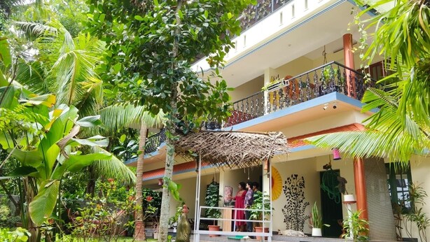 A multi-story building with a covered outdoor area, surrounded by lush greenery. - Aryavilla Heritage (Varkala)