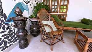 Ein Zimmer mit einem Rattan-Sessel, einem grünen Sofa und dekorativen Vasen.