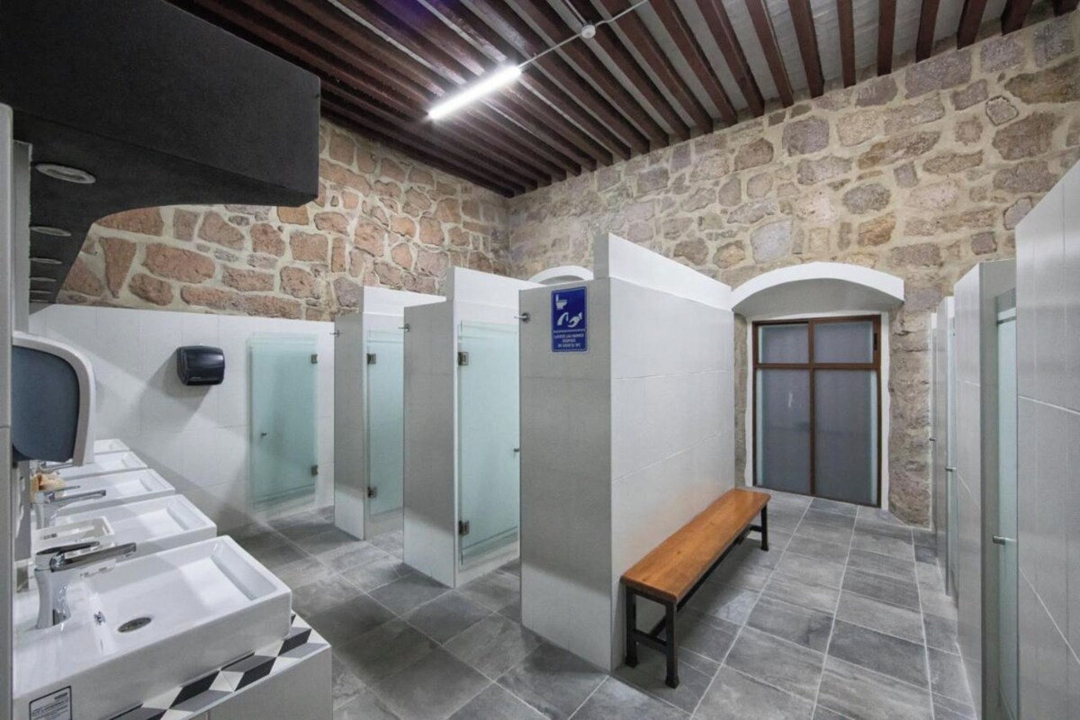 A public restroom with multiple stalls, a bench, and a sink area.