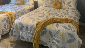 Une chambre avec deux lits, un ventilateur de plafond et des œuvres d’art accrochées au mur.