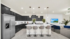 A modern kitchen with a central island, dark cabinets, stainless steel appliances, and pendant lighting. - Secluded 10 Bedroom Villa With Ocean Views 6282 (Davenport)