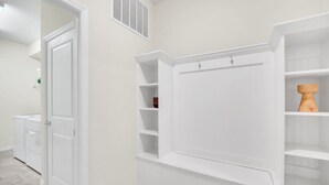 A hallway with white walls, a white door, and a built-in shelving unit with a wooden sculpture. - Secluded 10 Bedroom Villa With Ocean Views 6282 (Davenport)