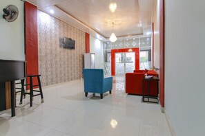A hotel lobby with a reception desk, seating area, and a view of the dining area. - Hotel O Ratu Residence (Medan)