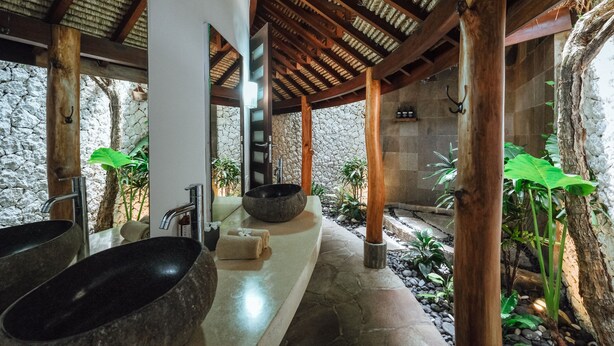 Un espace spa avec des murs en pierre, des poutres en bois et de grands récipients noirs.