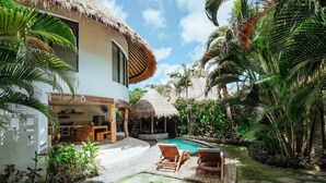 Une villa moderne dotée d’une piscine, d’une terrasse en bois et d’un luxuriant jardin tropical.