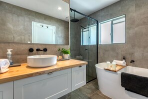 Un bagno moderno con un ampio lavabo bianco, una cabina doccia in vetro e una vasca da bagno.