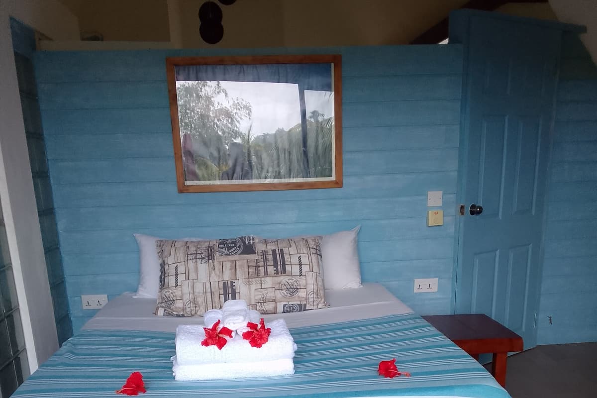 A bed with a striped bedspread, pillows, and a bench.