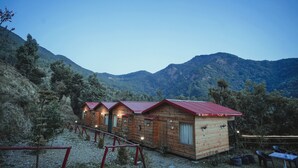 Una hilera de cabañas de madera con techos rojos, al pie de montañas.