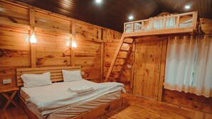 Un dormitorio de cabaña de madera con una cama, una escalera y literas.