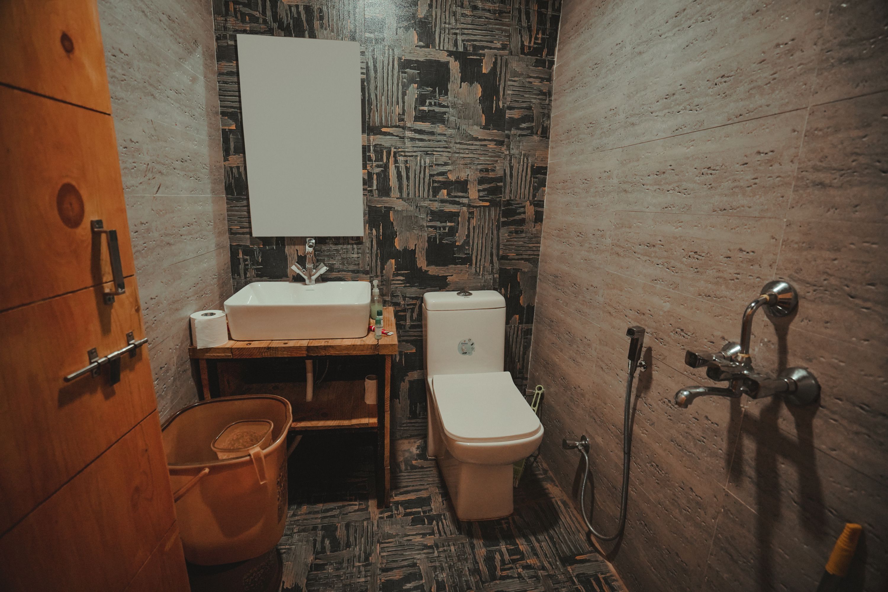 A compact bathroom with a wooden cabinet, a sink, a toilet, and a shower.