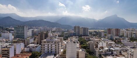 A cityscape with dense urban buildings, a mountain range in the background, and a clear sky.