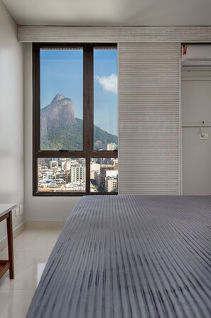 A hotel room with a large window offering a view of a mountain and cityscape. - 1806 (Rio de Janeiro)