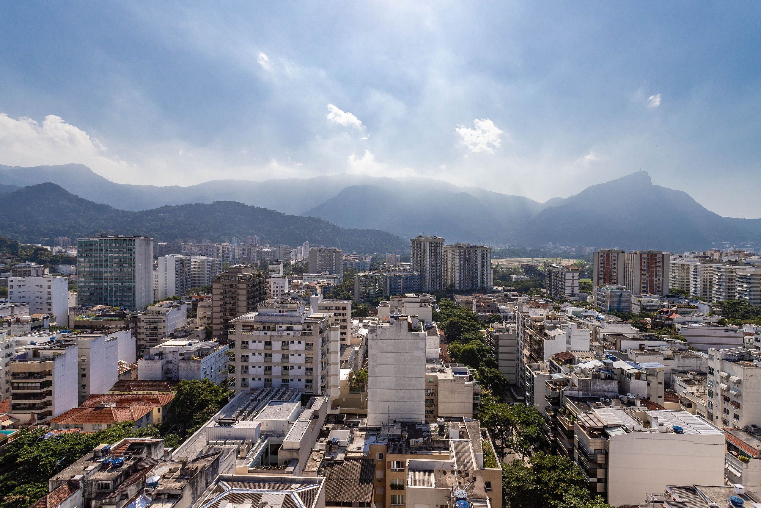 A cityscape with dense urban buildings, a mountain range in the background, and a clear sky.