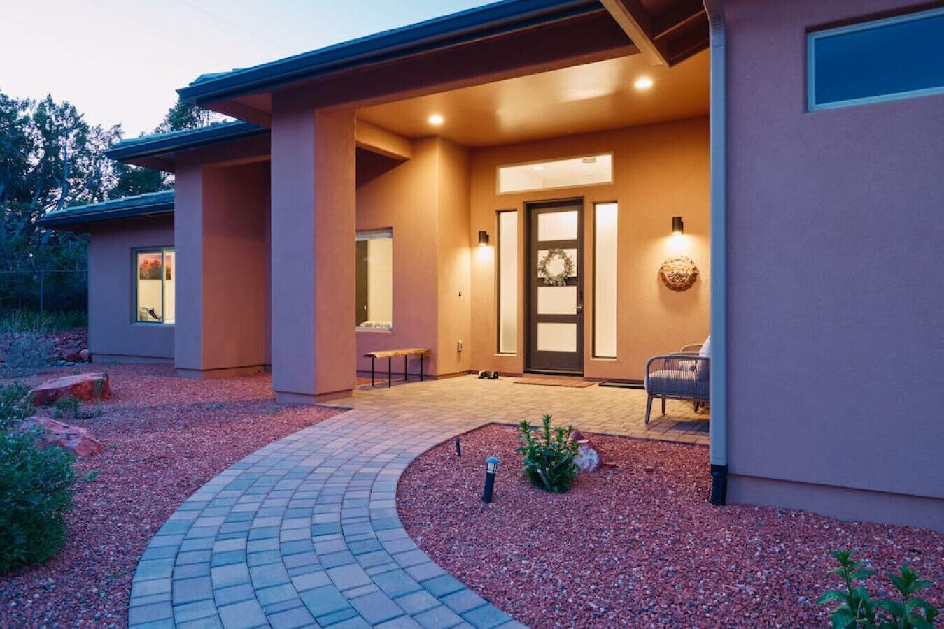 Une maison moderne avec une allée incurvée, un porche et une porte ornée d’une guirlande.