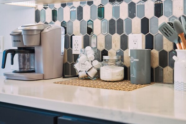 A kitchen counter with a coffee maker, jars of sugar, and a spice container.