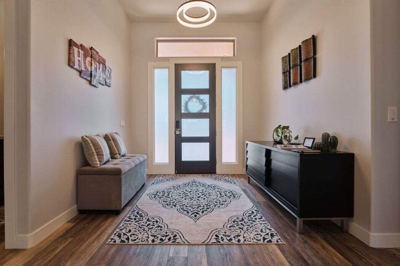 A hallway with a bench, a console table with decorative items, and a patterned rug.