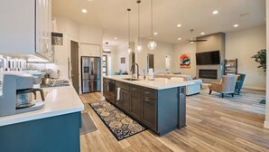A modern kitchen with a central island, built-in appliances, and pendant lighting. - Spacious Home with Thunder Mountain Views! (Sedona)